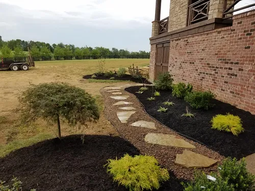 A brick building with a lush green garden in front of it.