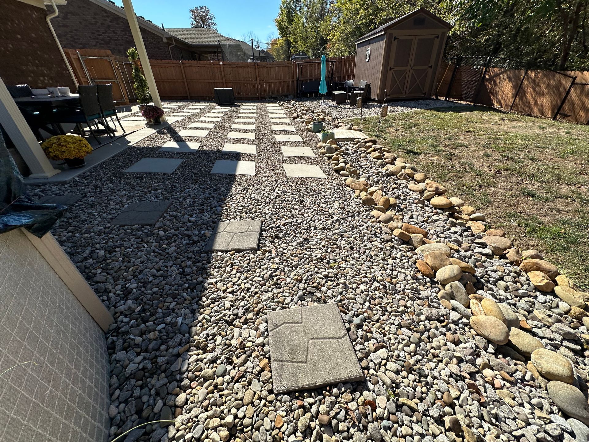 A gravel path leading to a shed in a backyard.