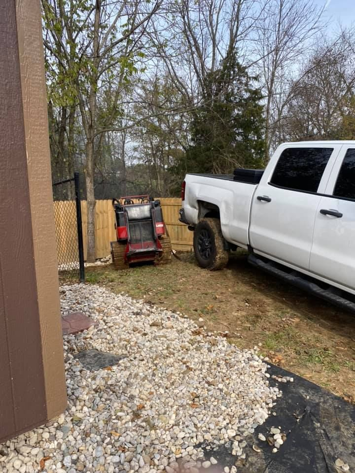 A white truck is parked in a yard next to a lawn mower.