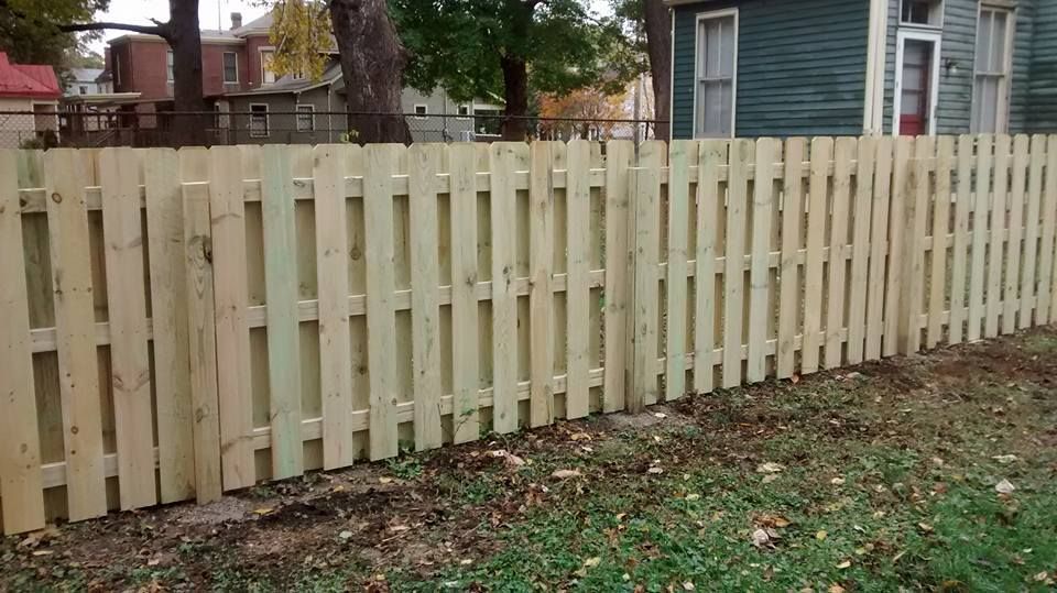 A wooden fence is sitting in the grass in front of a house.