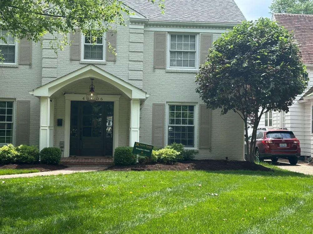 A white house with a red car parked in front of it