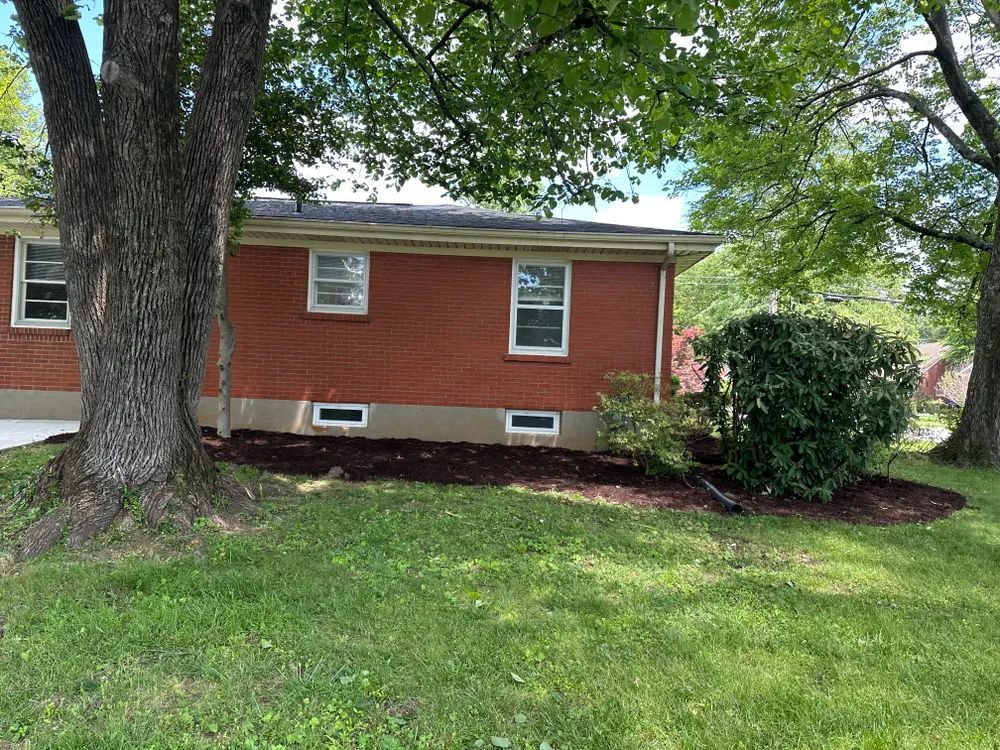 A red brick house with a large lawn in front of it.
