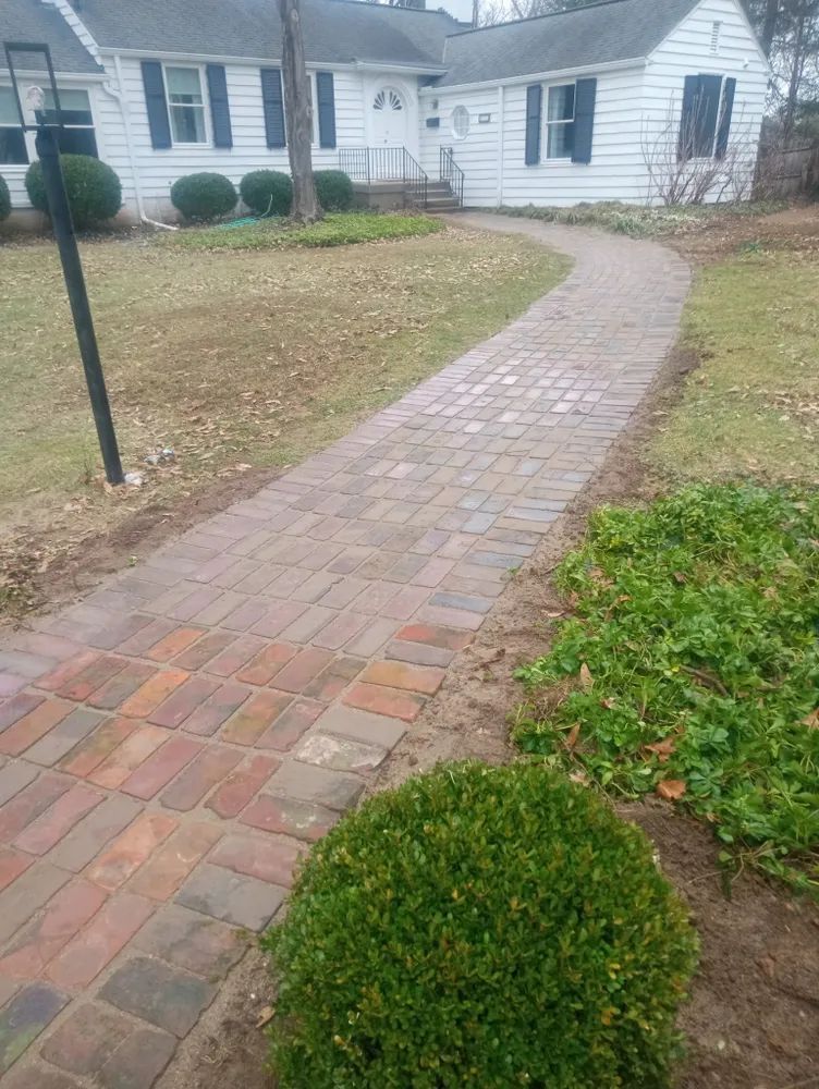 A brick walkway leading to a white house.