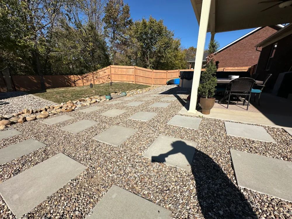A shadow of a person is cast on a gravel patio.