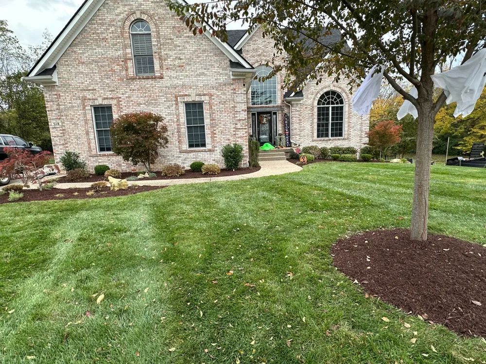A large brick house with a lush green lawn in front of it.