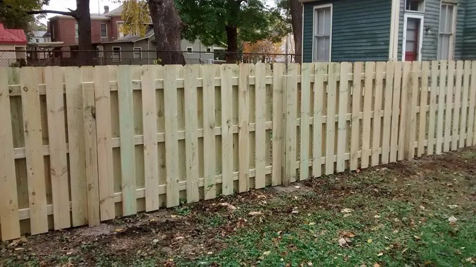 A wooden fence is in the backyard of a house.