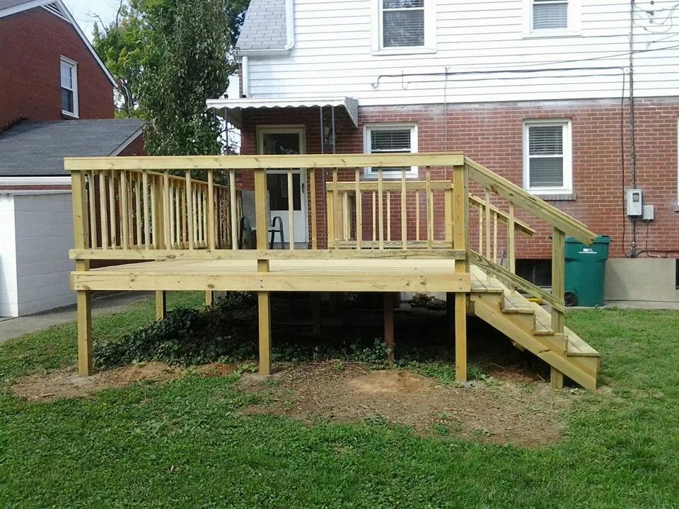 A wooden deck with stairs in front of a brick house