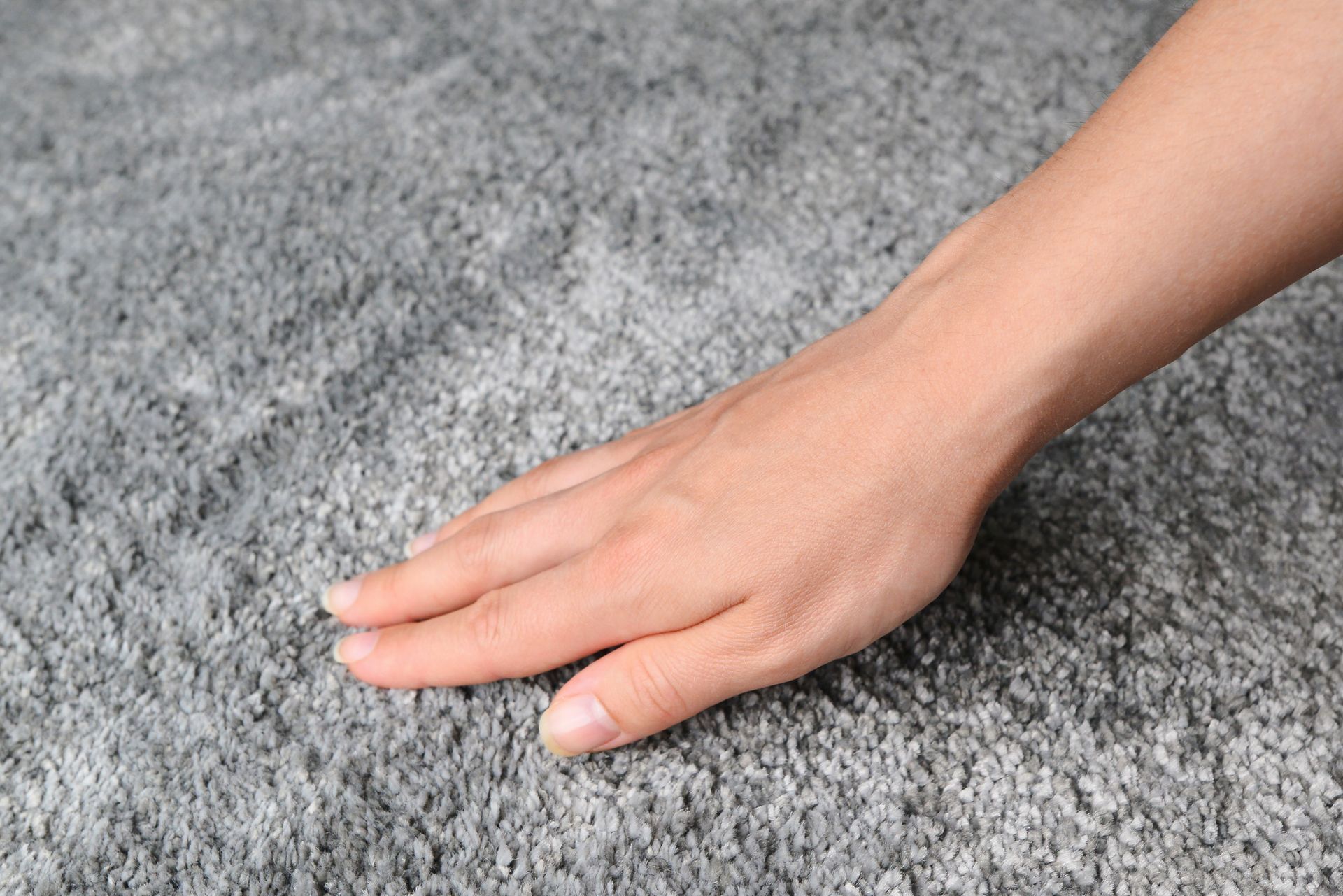 Hand resting on a gray, textured carpet.