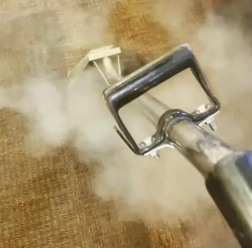 Carpet steam cleaner in action, emitting steam.