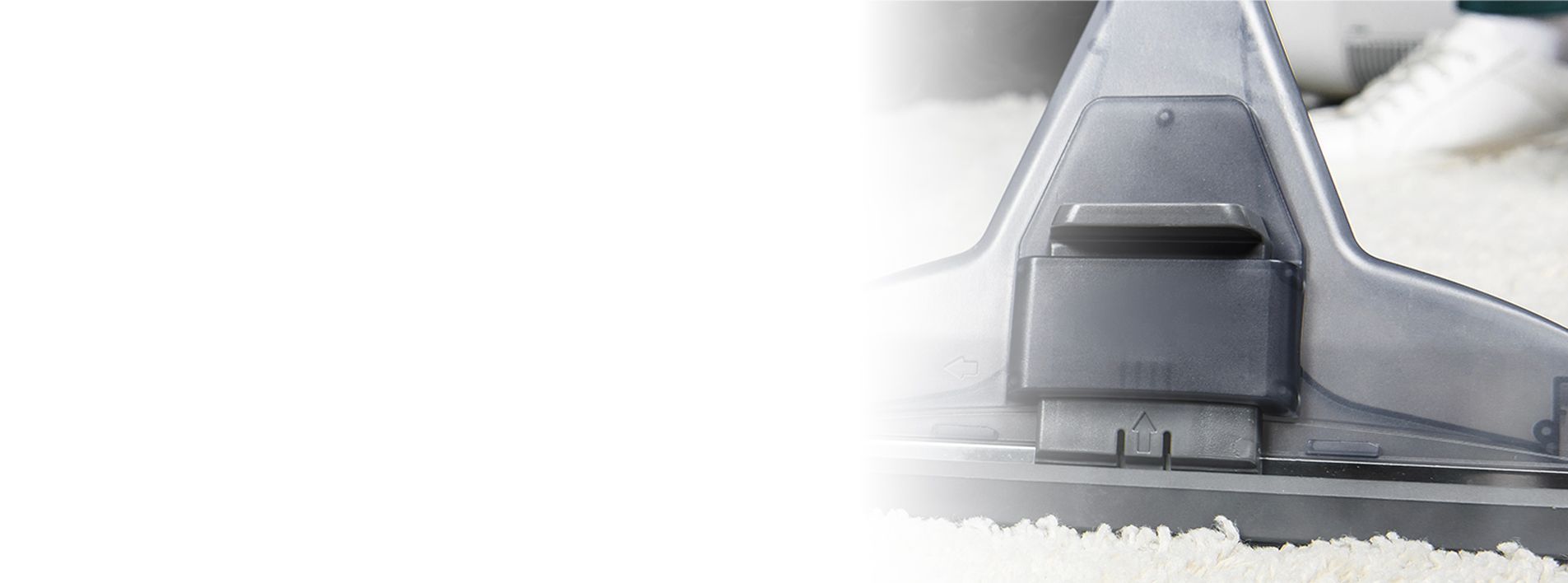 Close-up of a vacuum cleaner head on a white rug.