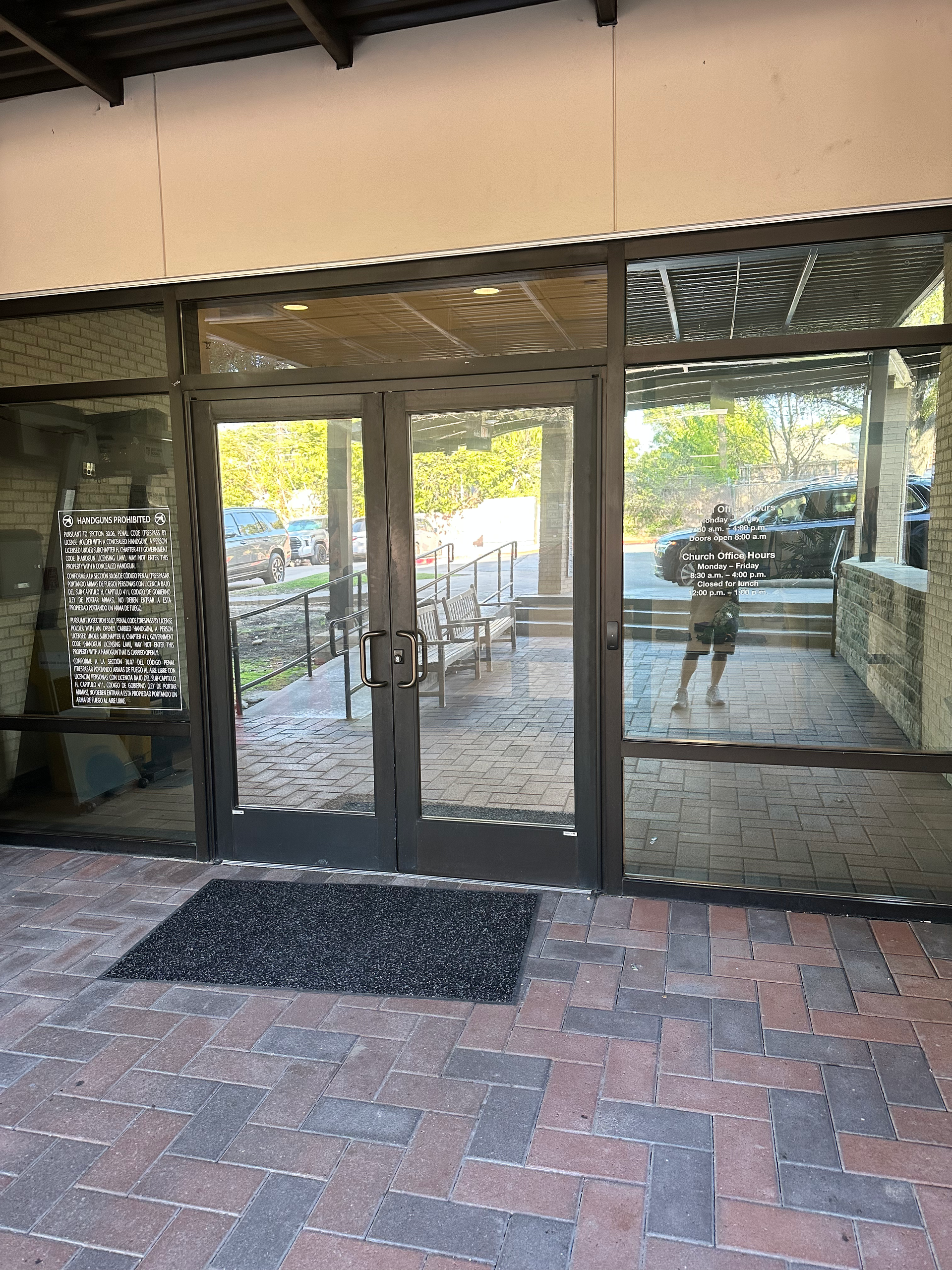 Glass doors and windows, brick patio, person's reflection, outdoor seating visible through the glass.