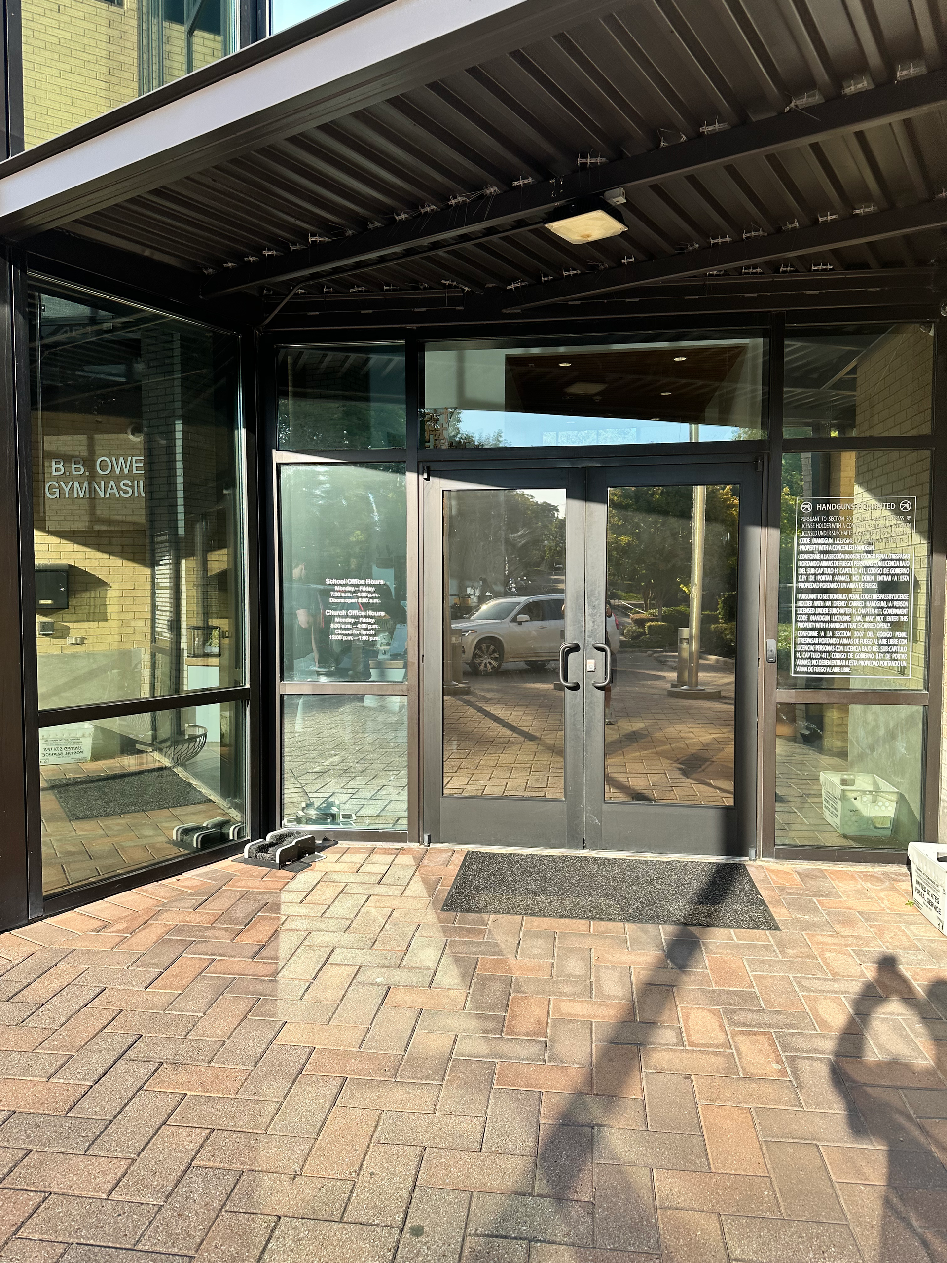 Glass storefront with brick walkway. Double doors with a welcome mat, surrounded by windows.