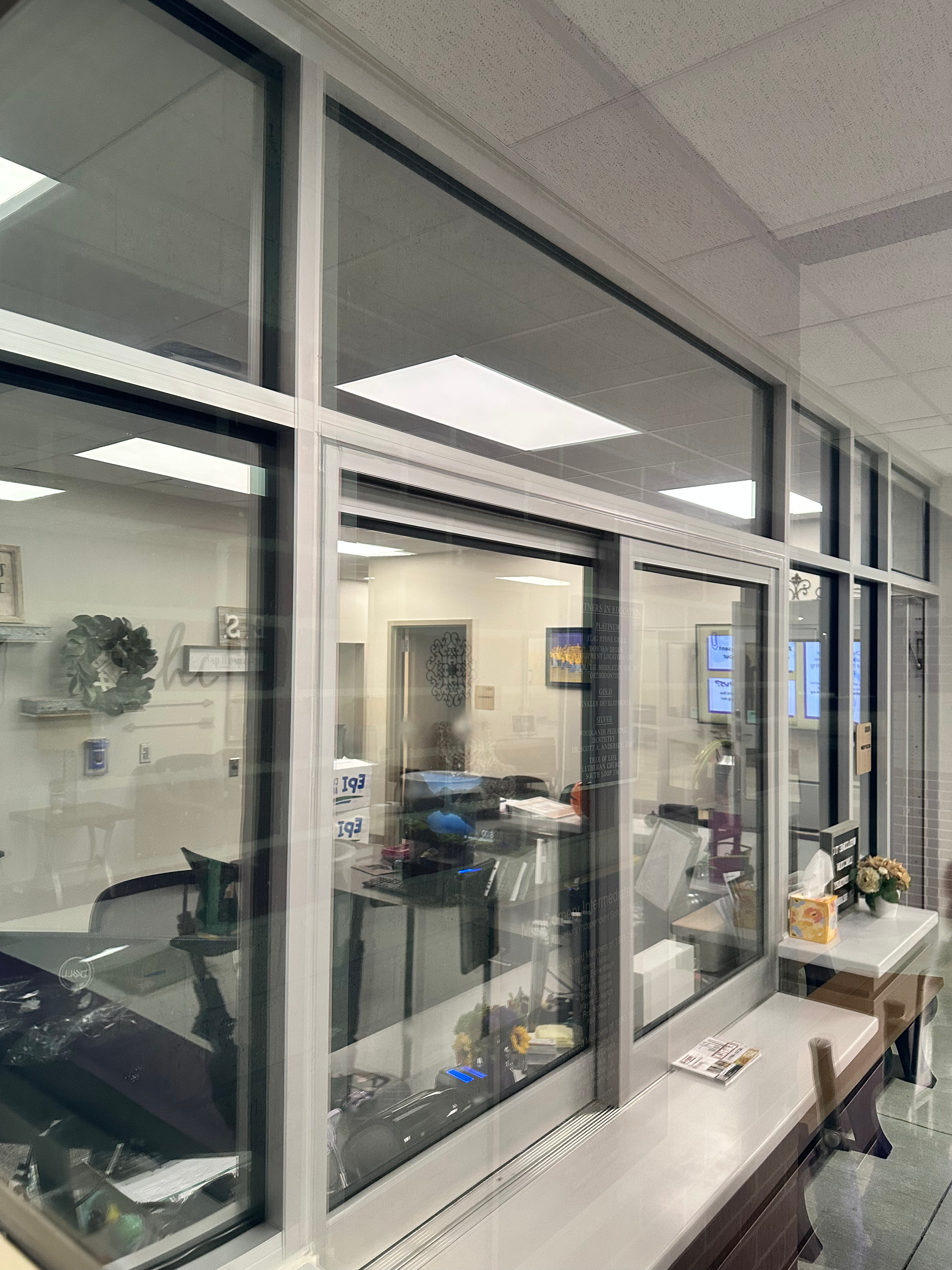 Glass office windows with a view into a workspace, likely a medical or dental office.