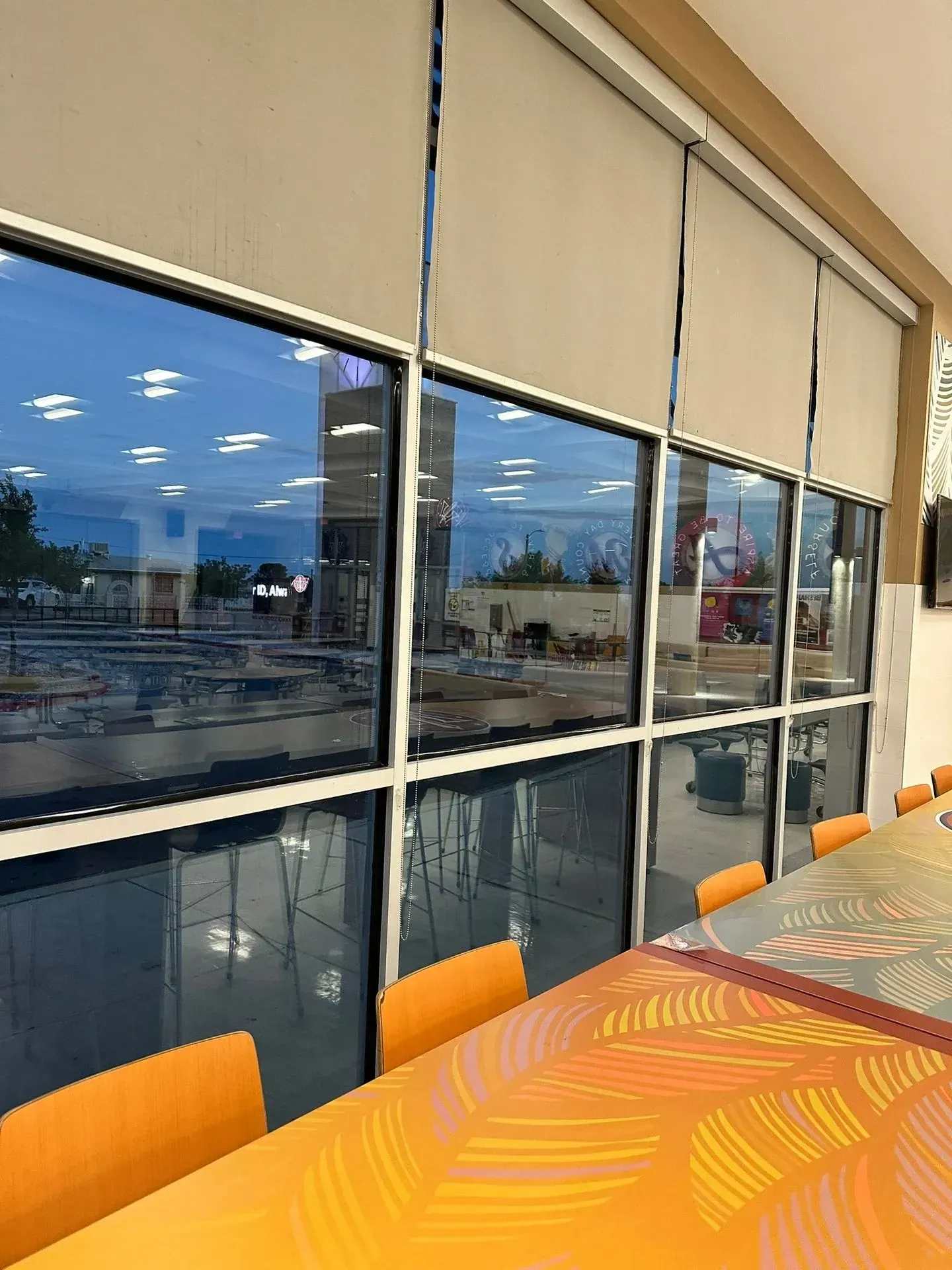 Restaurant interior with large windows overlooking a construction site. Orange table and chairs visible.