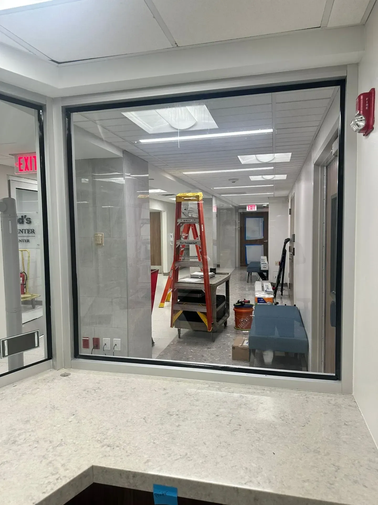 Hallway with a large window under construction; ladder, tools, and building materials visible.