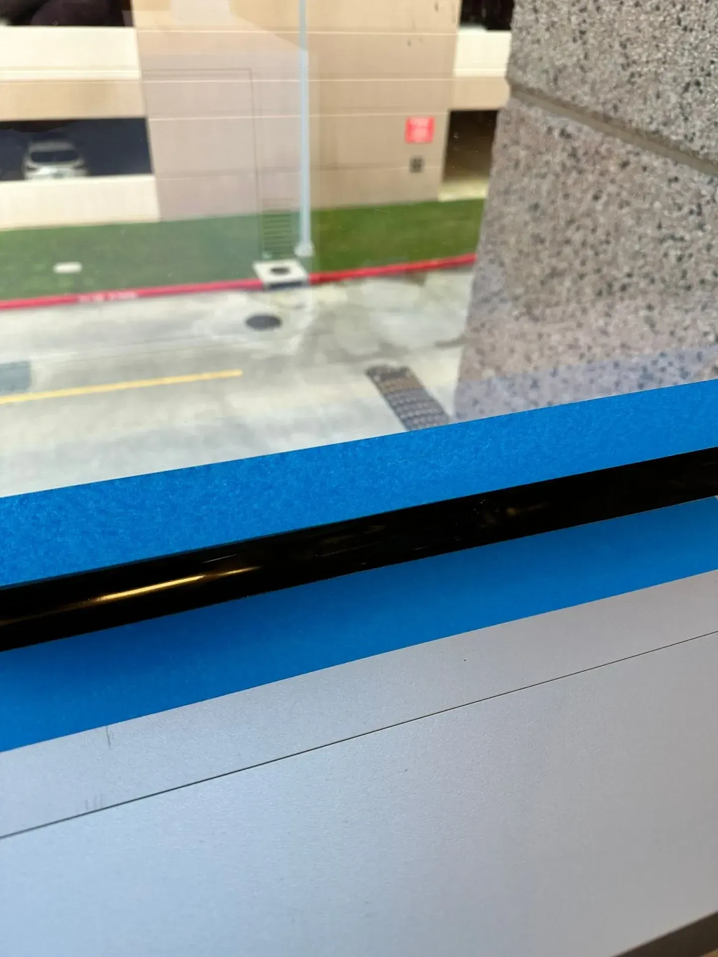 Blue and white surface with black bar, next to a window overlooking a street.