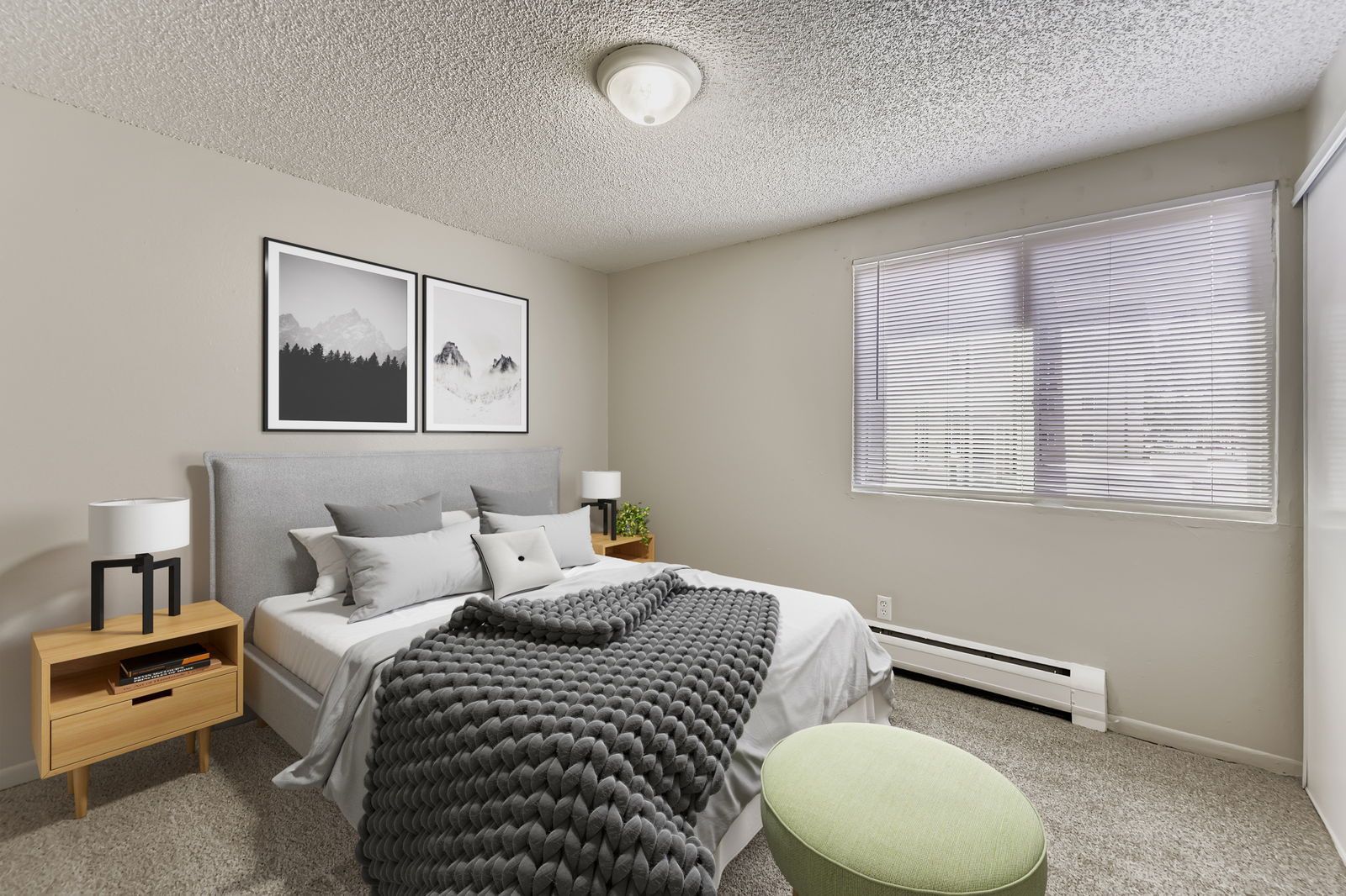 Bedroom in a modern apartment with a bed, two nightstands, and a large window with blinds.
