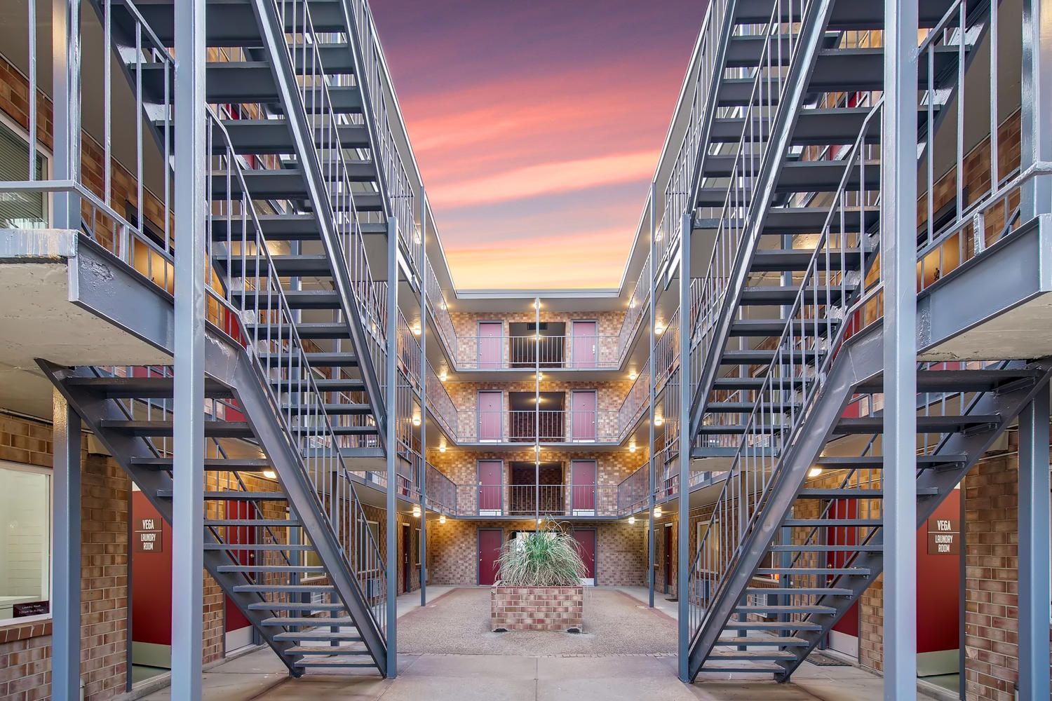 Exterior courtyard of apartment complex with metal staircases and brick walls at sunset