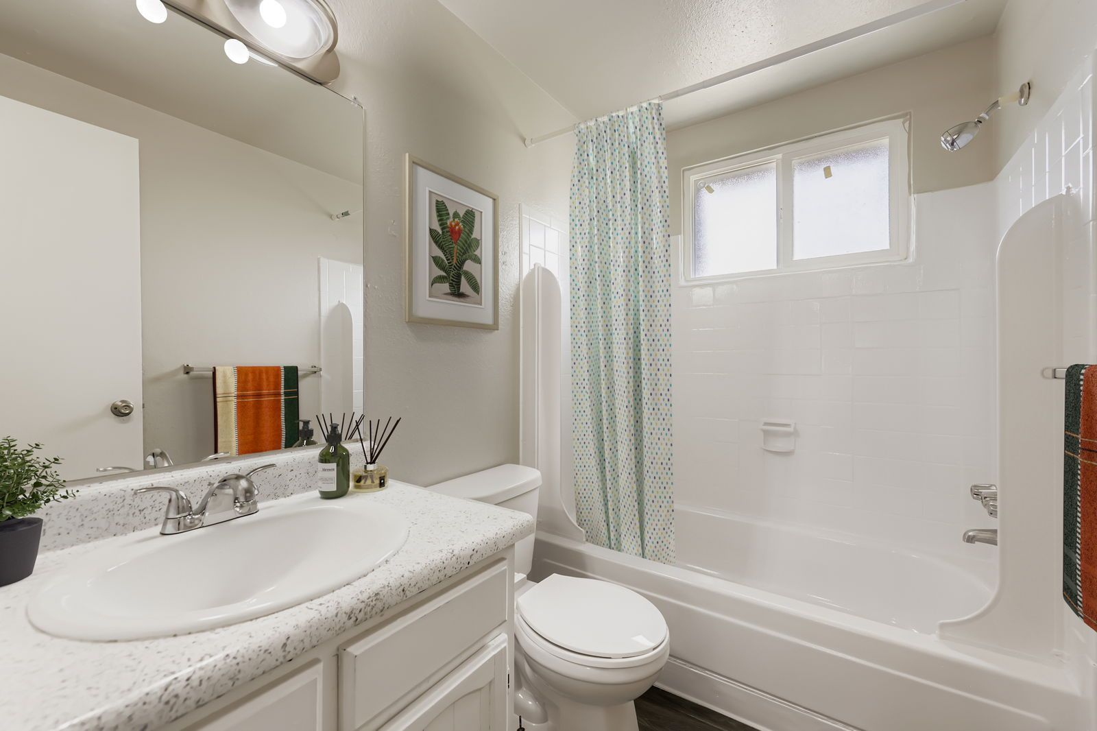 Bathroom with vanity, mirror, toilet, and bathtub/shower with a curtain.