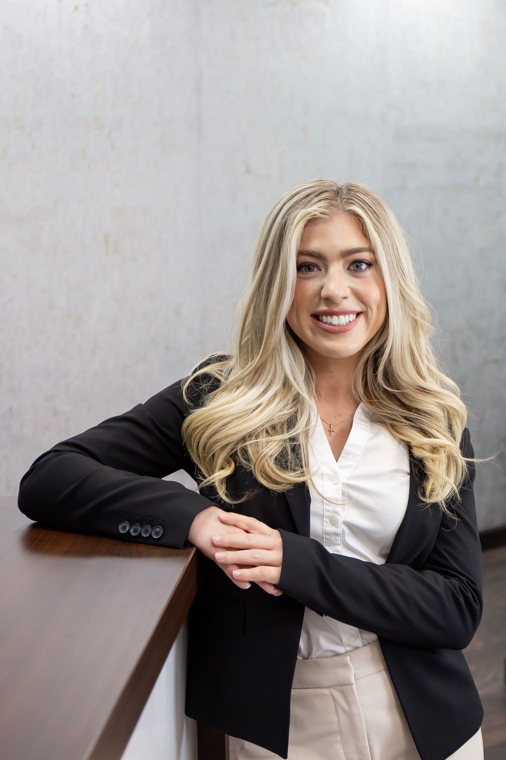 Kendelle Knapp — Woman wearing black suit with one leg crossed. 