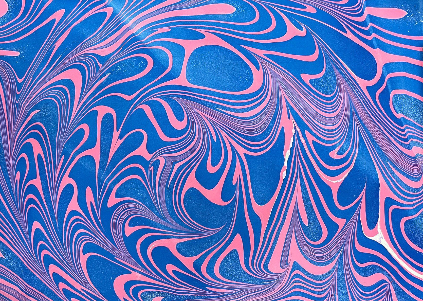 Swirling freeform marbled paper in pink and blue.