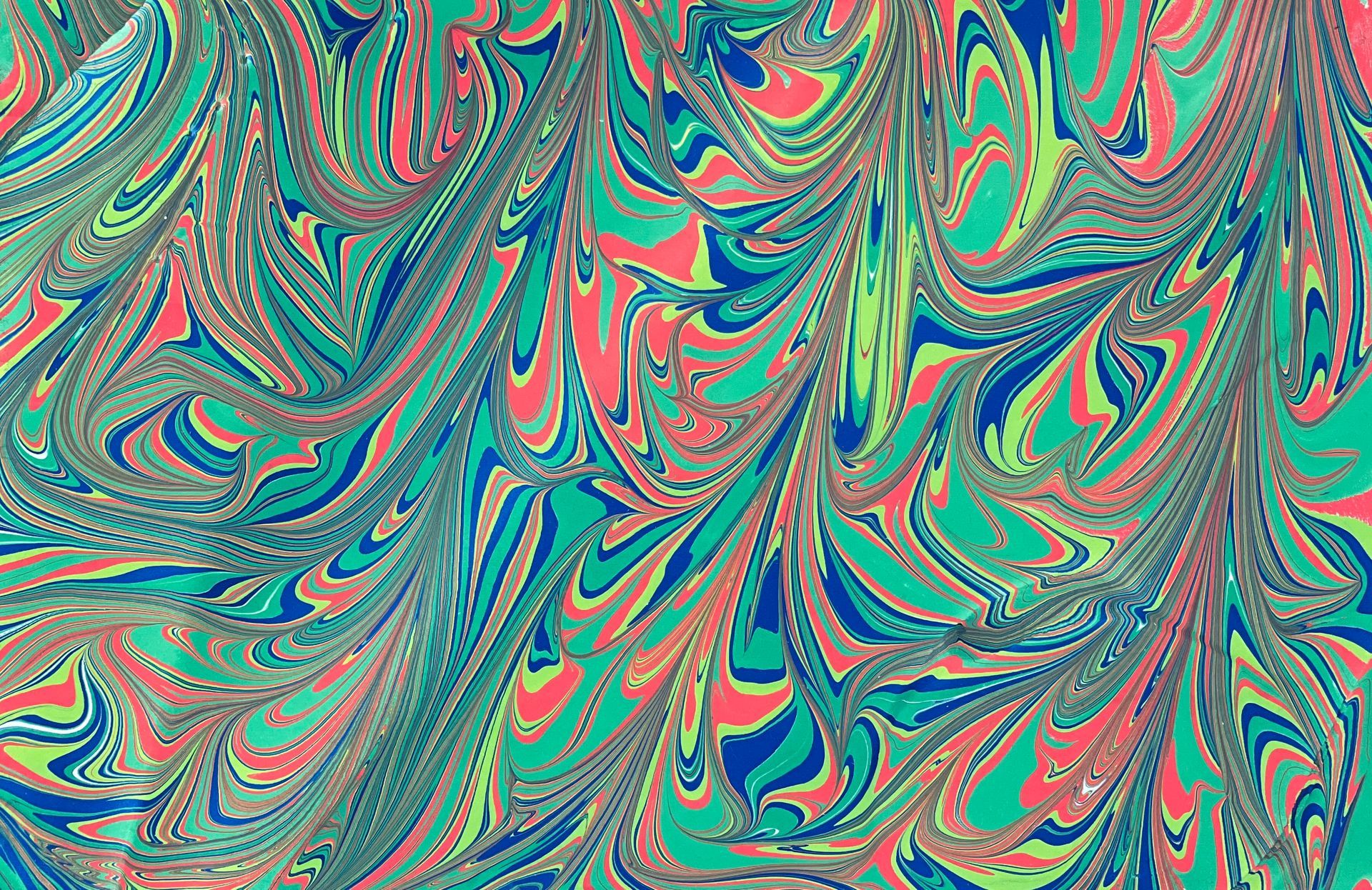 Green, red and blue swirling colors in a marbled artwork.