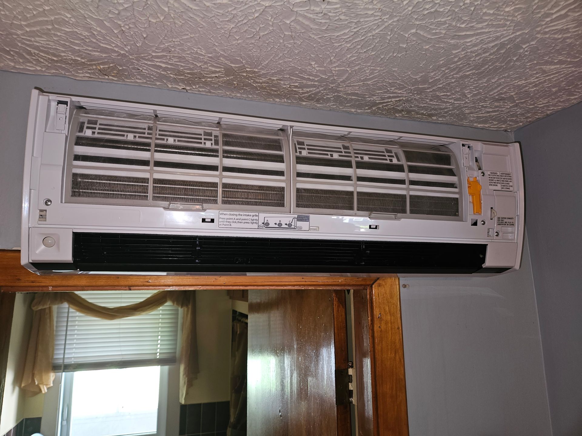 A white air conditioner is hanging from the ceiling in a room.