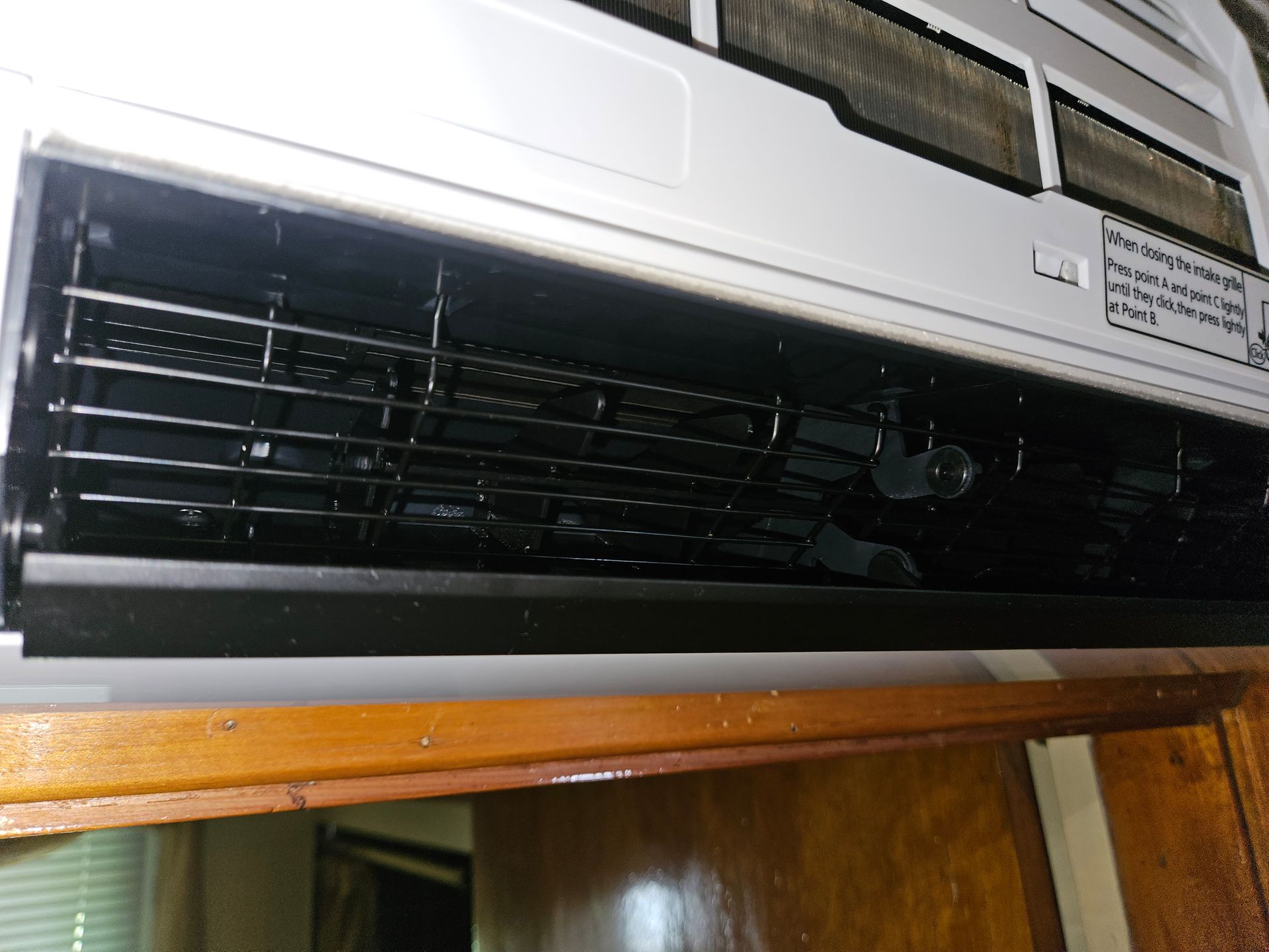 A white air conditioner is hanging from the ceiling in a room.