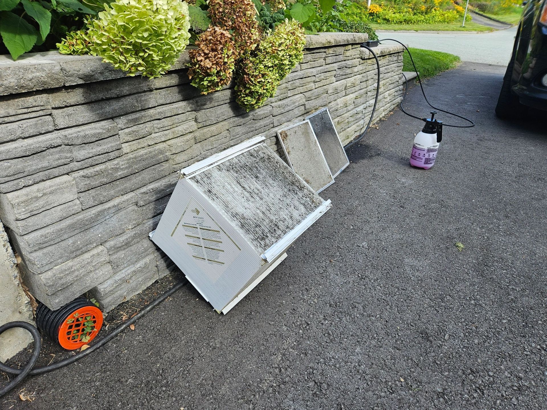 A beehive is sitting on the side of the road next to a brick wall.