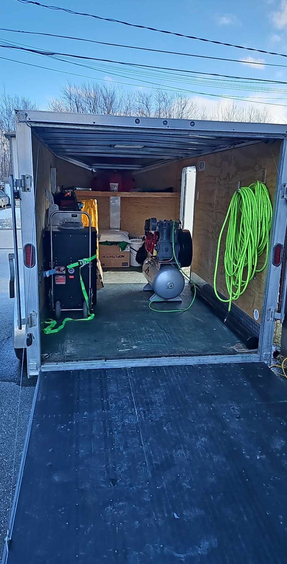 The inside of a trailer filled with tools and a hose.