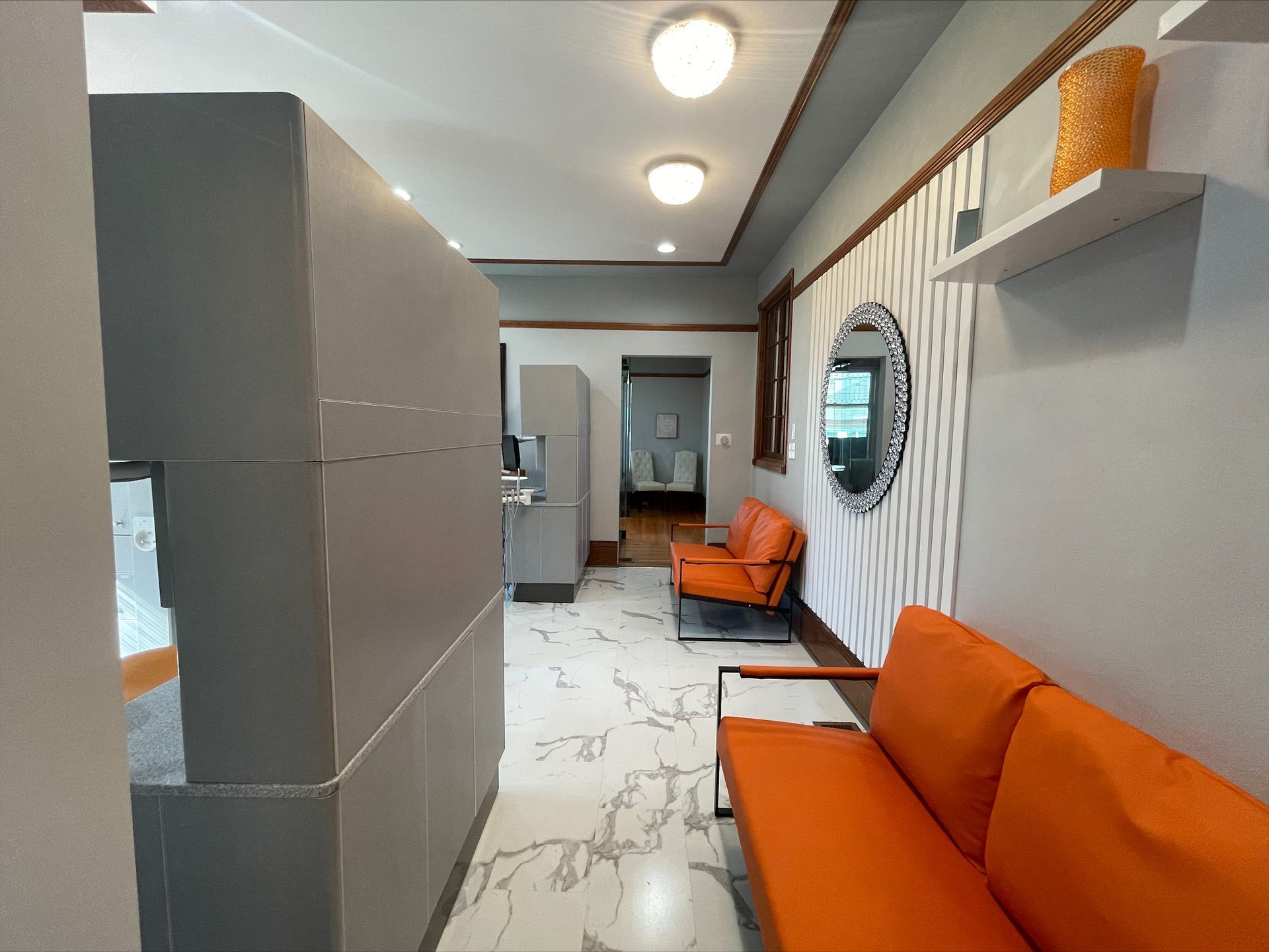 A waiting room with a couch and chairs and a mirror on the wall.