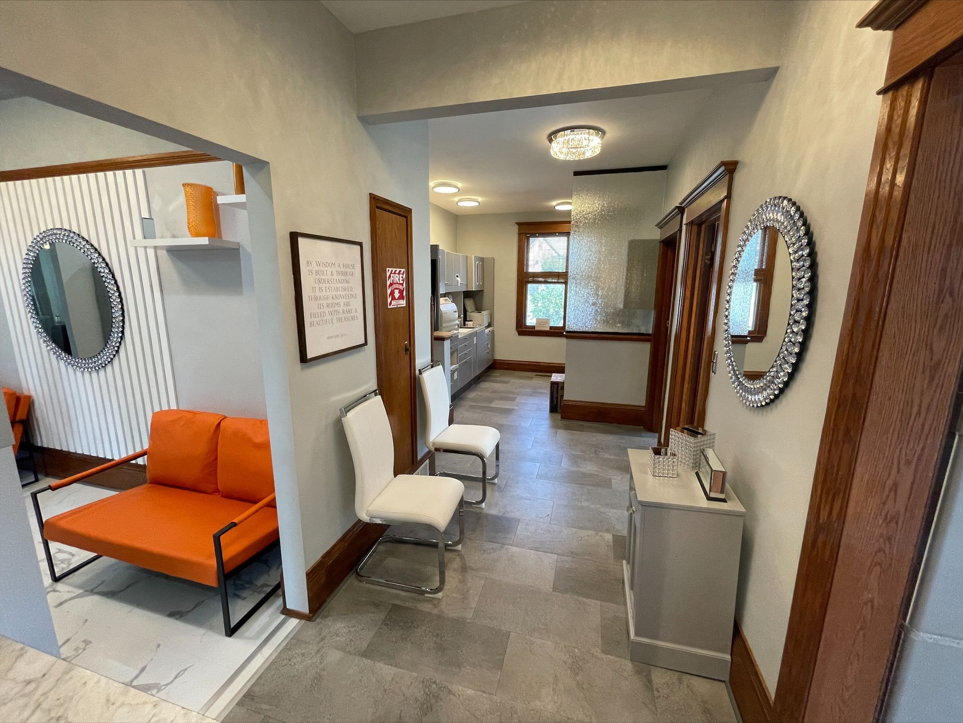 A waiting room with a couch , chairs and a mirror.