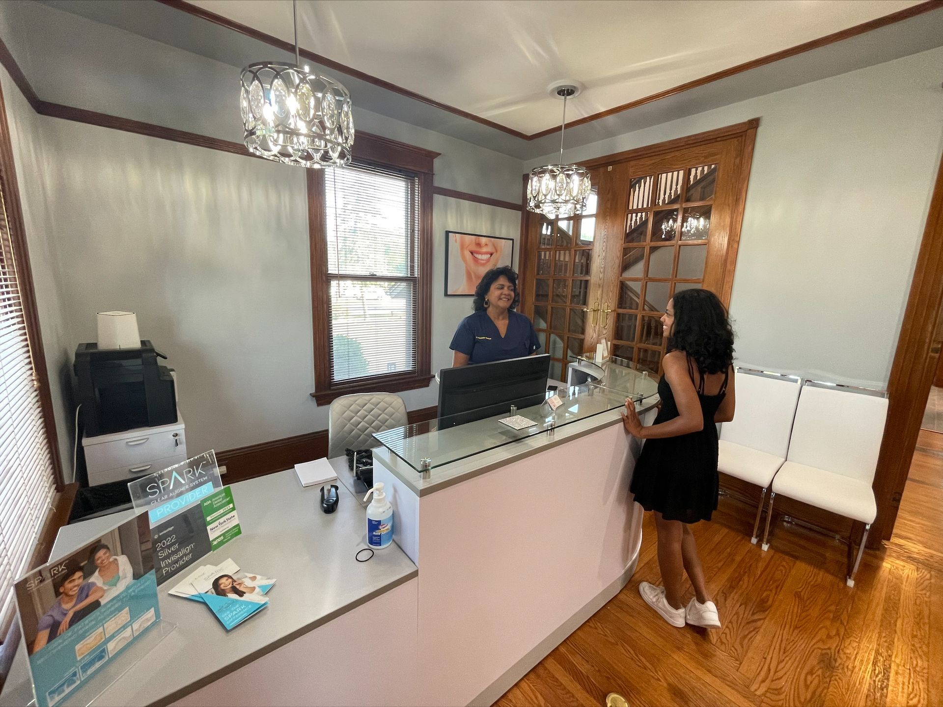 A woman is standing in front of a desk in a dental office.
