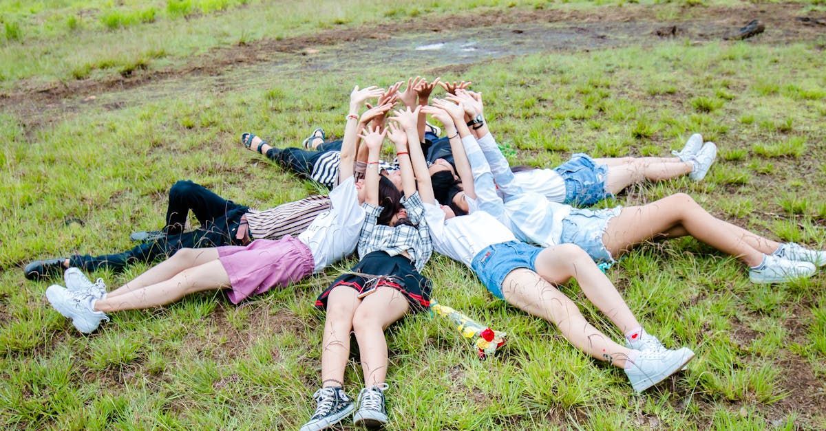 Group of friends form in circle while lying on the grass while hands on top