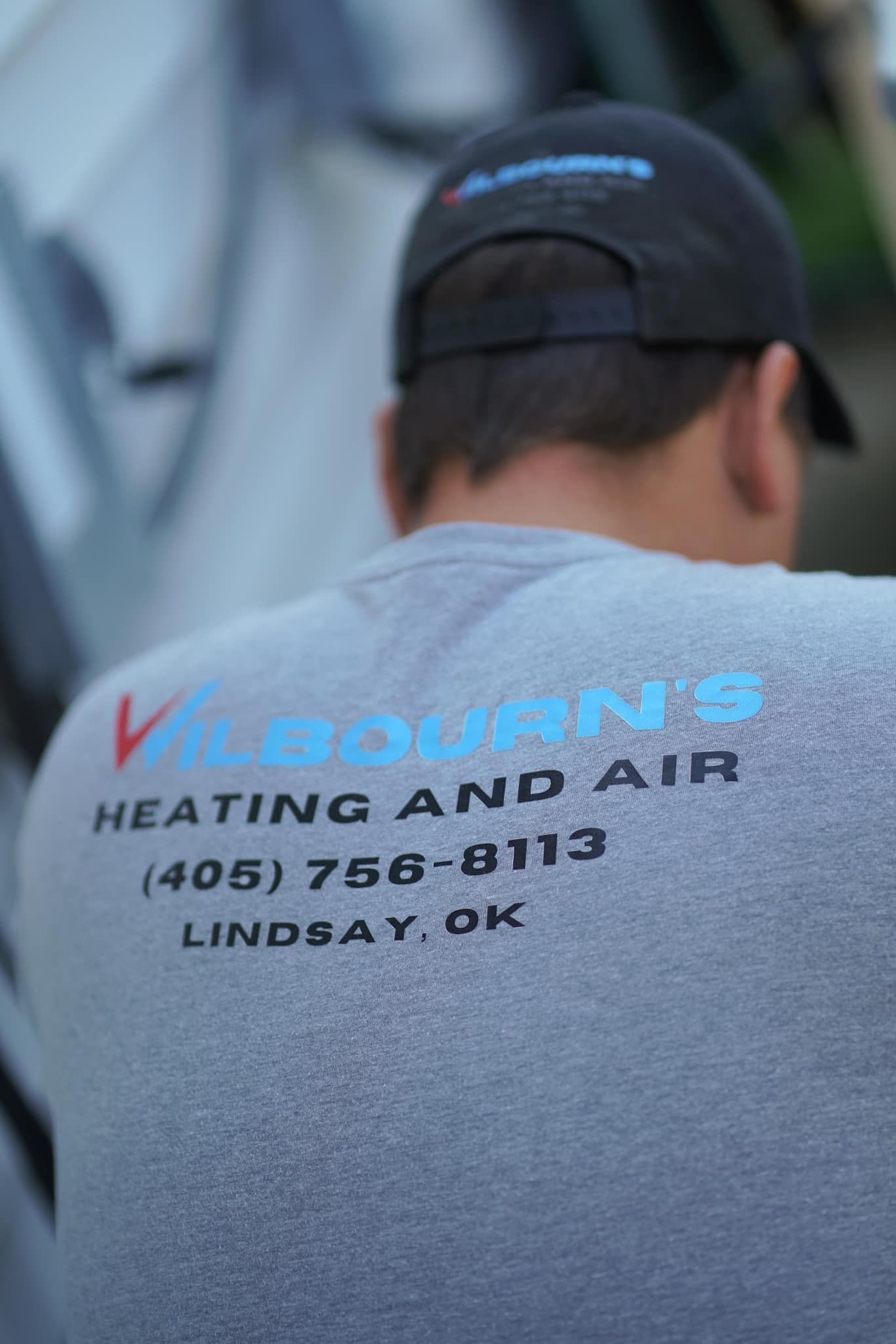 A man wearing a grey shirt that says heating and air