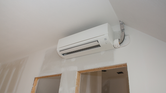 A white air conditioner is hanging from the ceiling in a room.