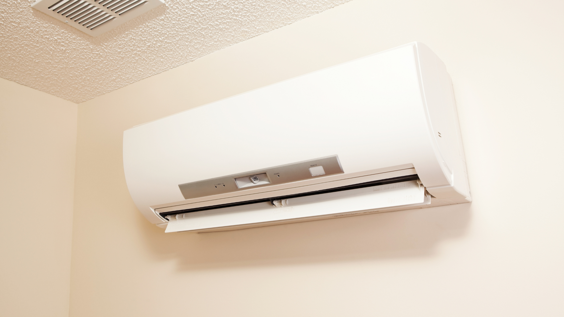 A white air conditioner is hanging on a wall in a room.