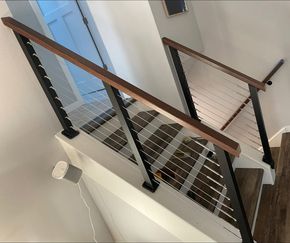 Stairwell with black metal railing, wood handrail, and white perforated steps