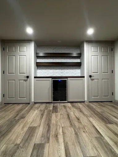 Built-in cabinets and shelves centered on a wall, with wood-look flooring and recessed ceiling lights.