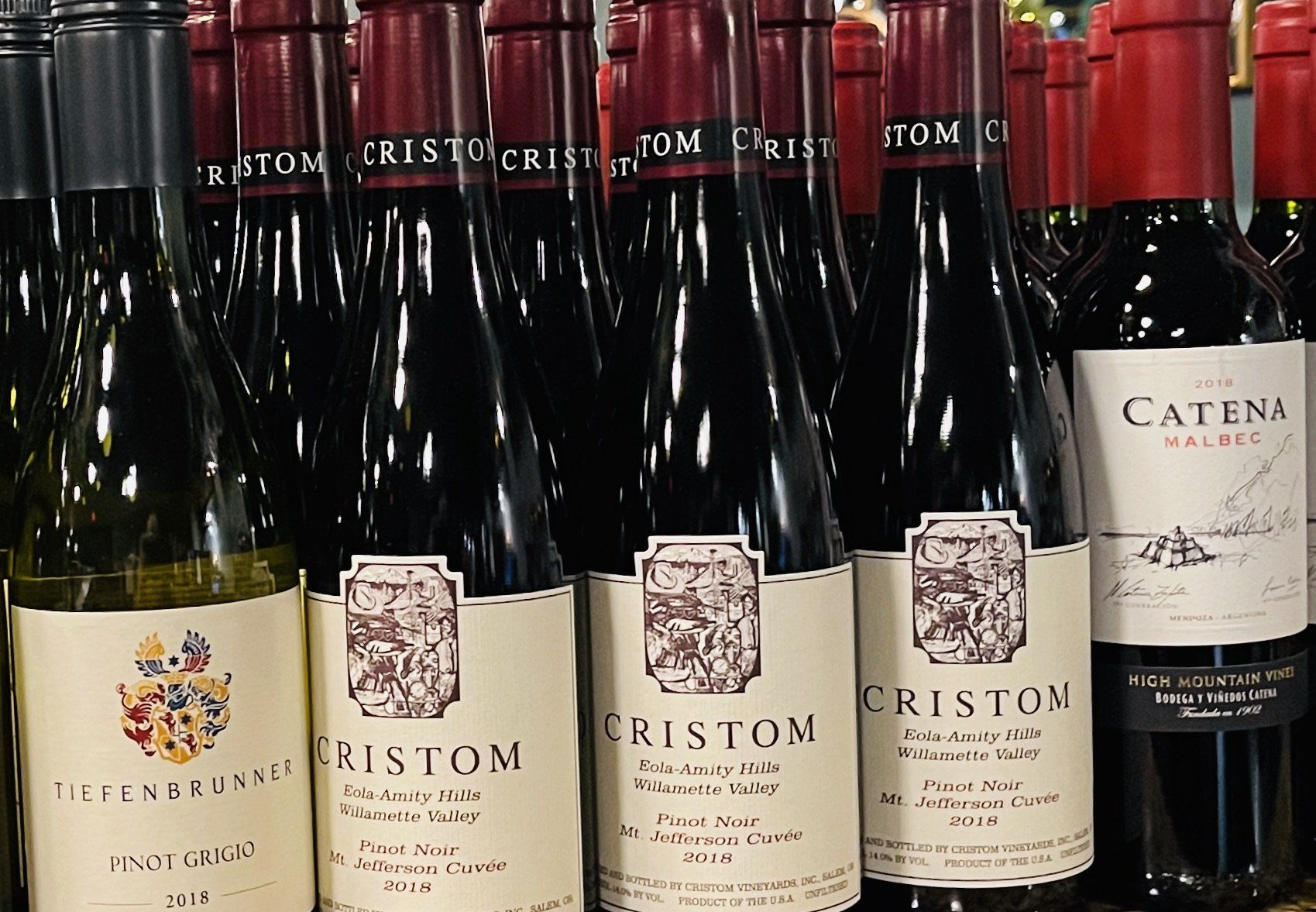 Several bottles of cristom wine are lined up on a shelf