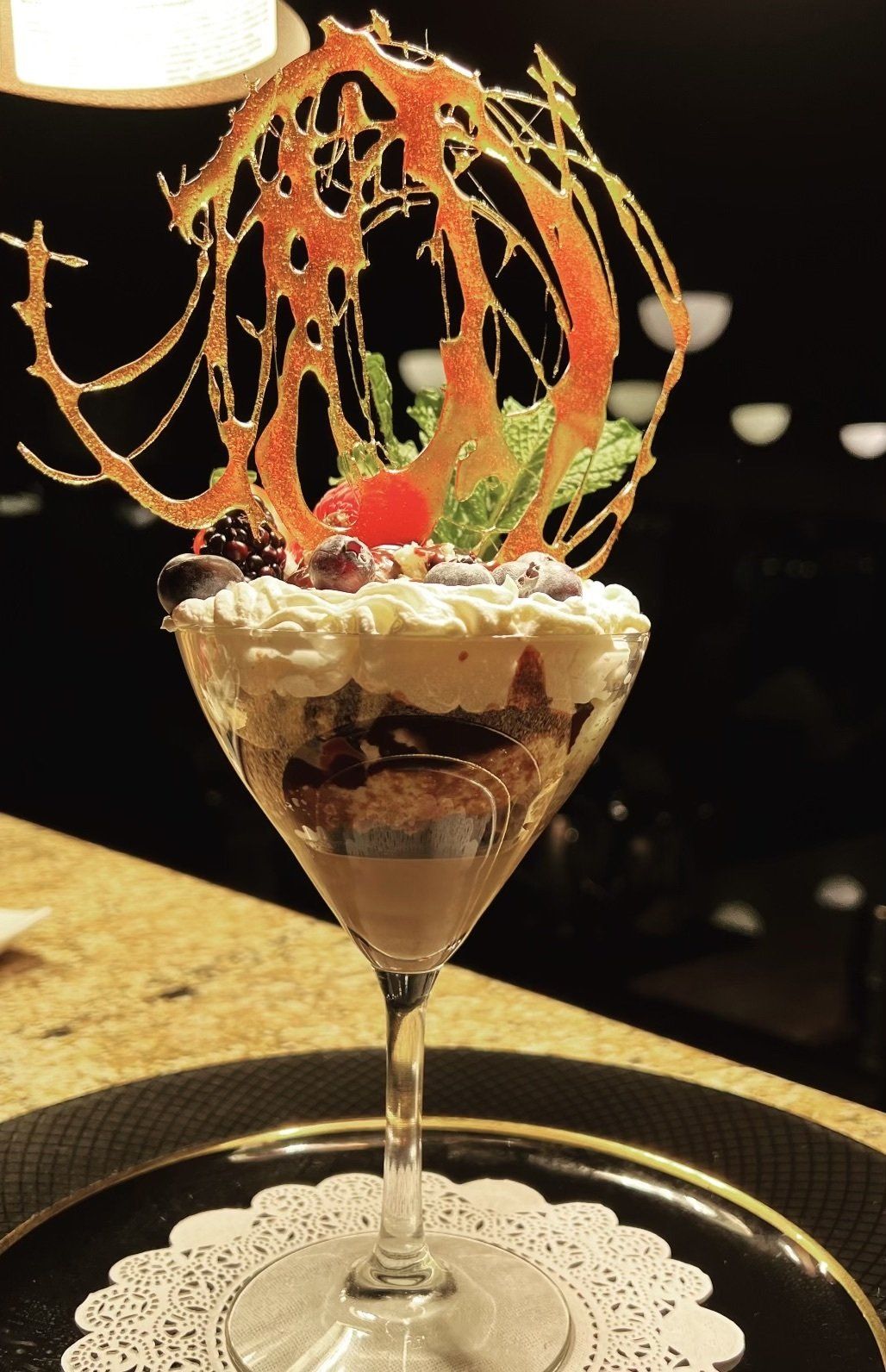 A dessert in a martini glass with whipped cream and berries on top