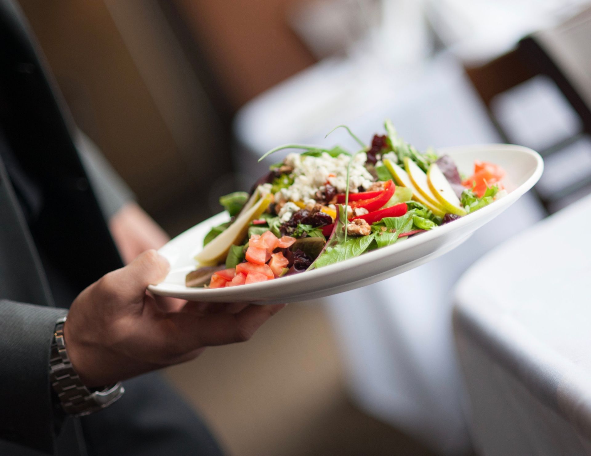 A person is holding a plate of salad in their hand.