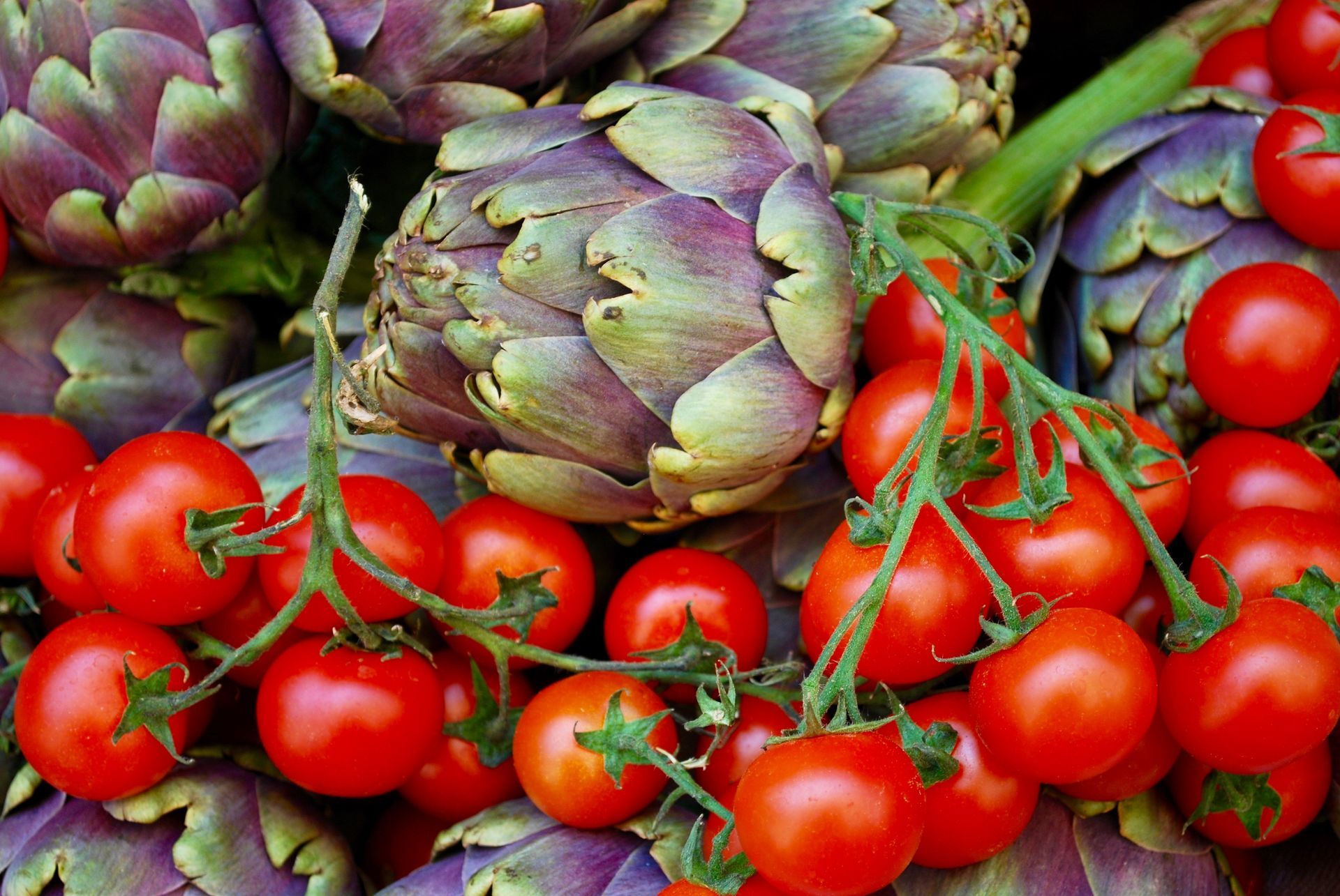 A bunch of artichokes and tomatoes on a vine