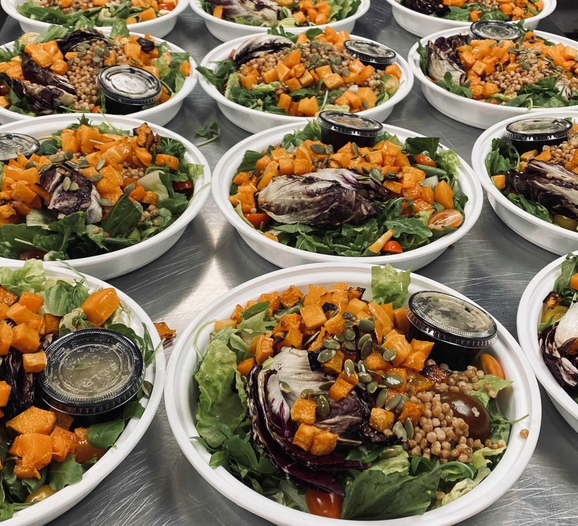 A bunch of bowls of salad are sitting on a table.