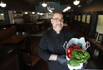 A chef is holding a bag of vegetables in a restaurant.