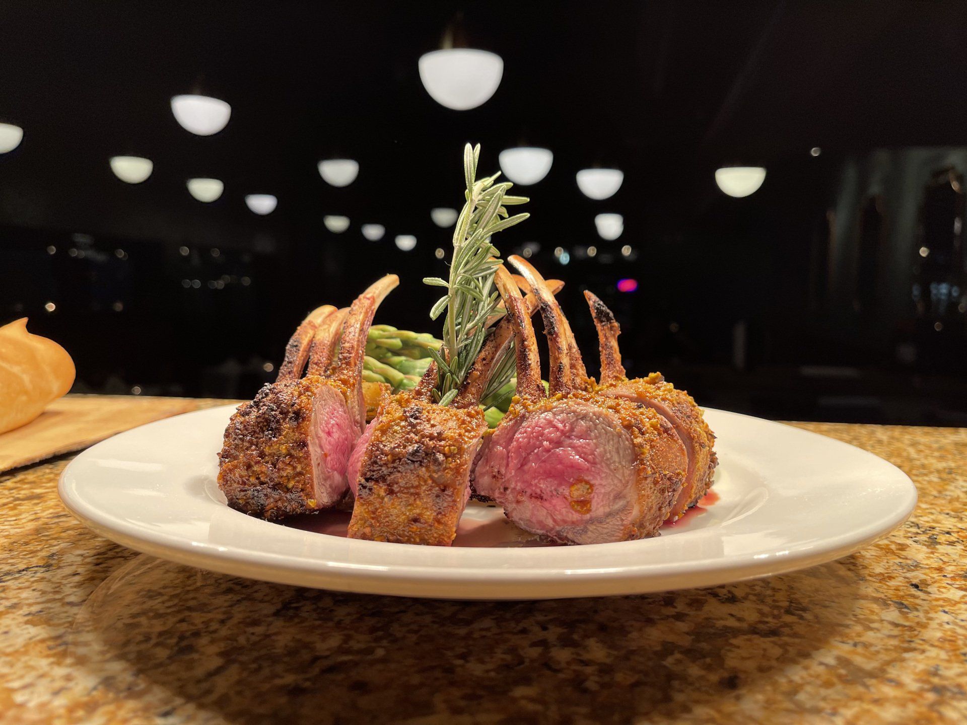 A white plate topped with lamb chops and green beans on a counter.