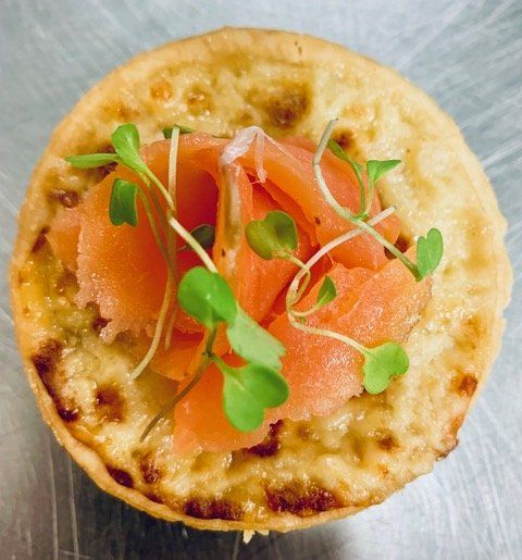 A pizza with smoked salmon and green sprouts on top