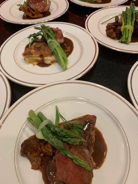Several plates of food on a table including asparagus and meat