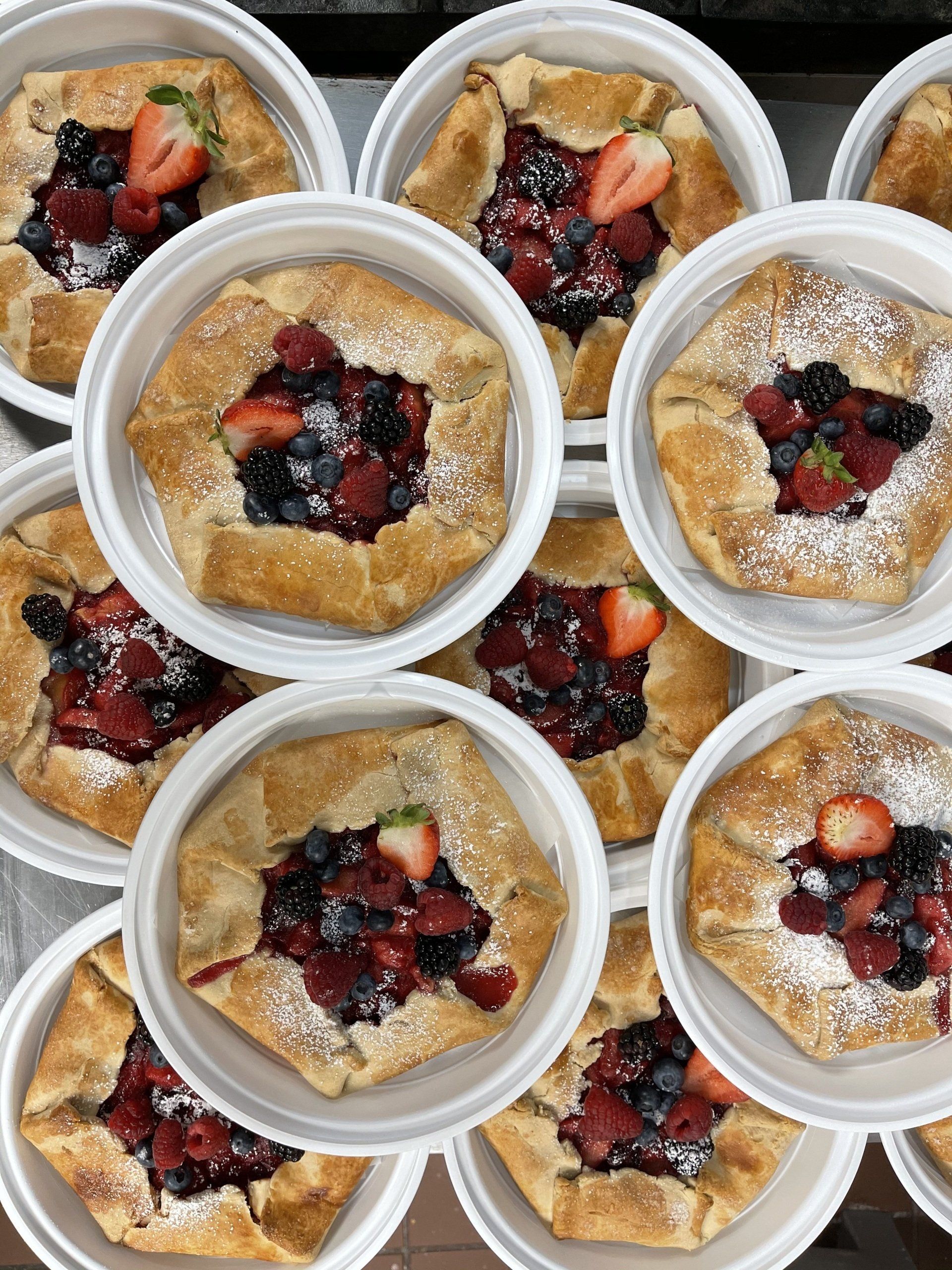 A bunch of desserts with berries and powdered sugar on them