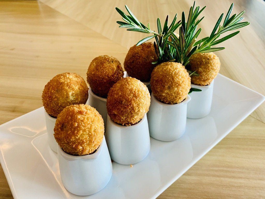 A white plate topped with fried food balls and rosemary.